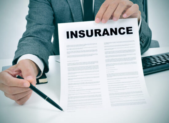 a young man in suit in his office showing an insurance policy and pointing with a pen where the policyholder must to sign